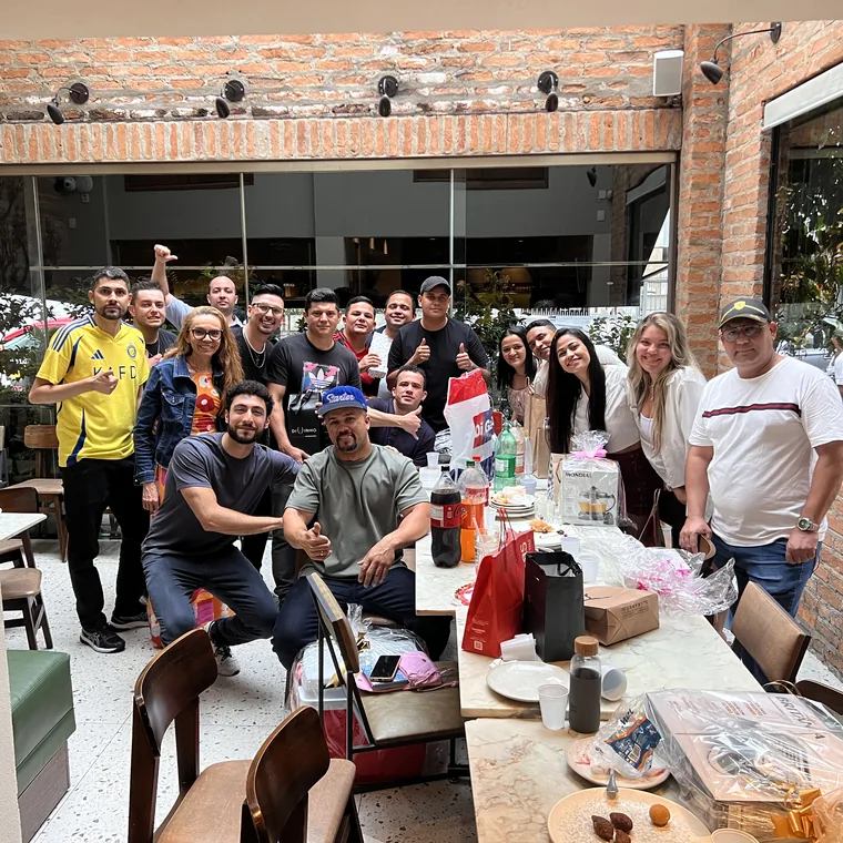 Time do Grupo Insalata comemorando reunido em um pátio de tijolo aparente