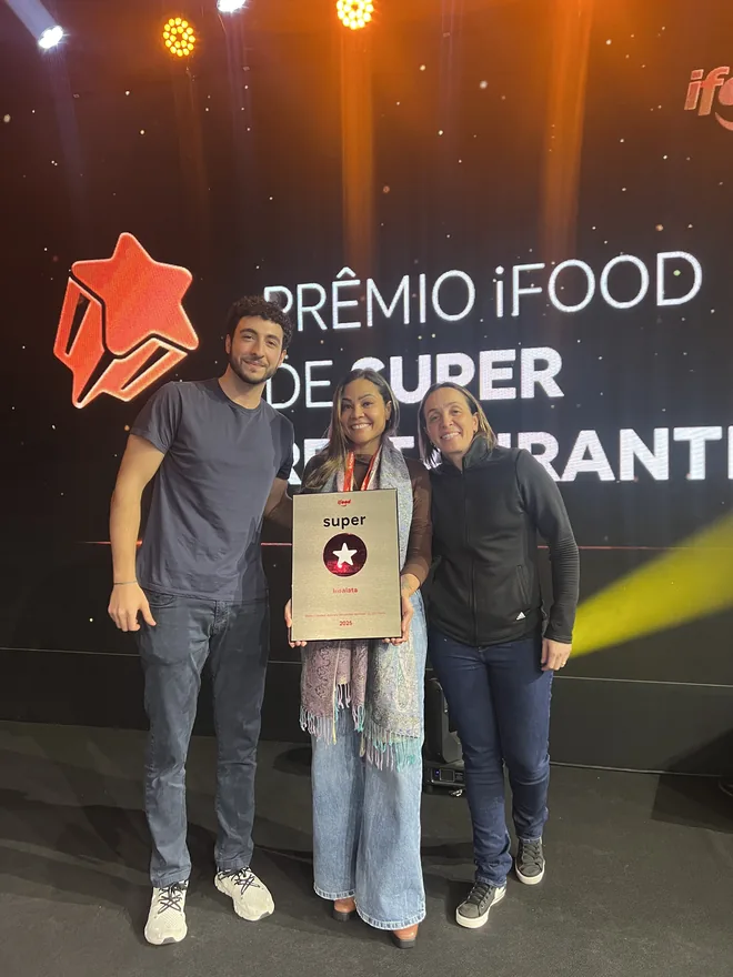Três integrantes do Grupo Insalata segurando a placa do prêmio iFood Super Restaurantes 2025